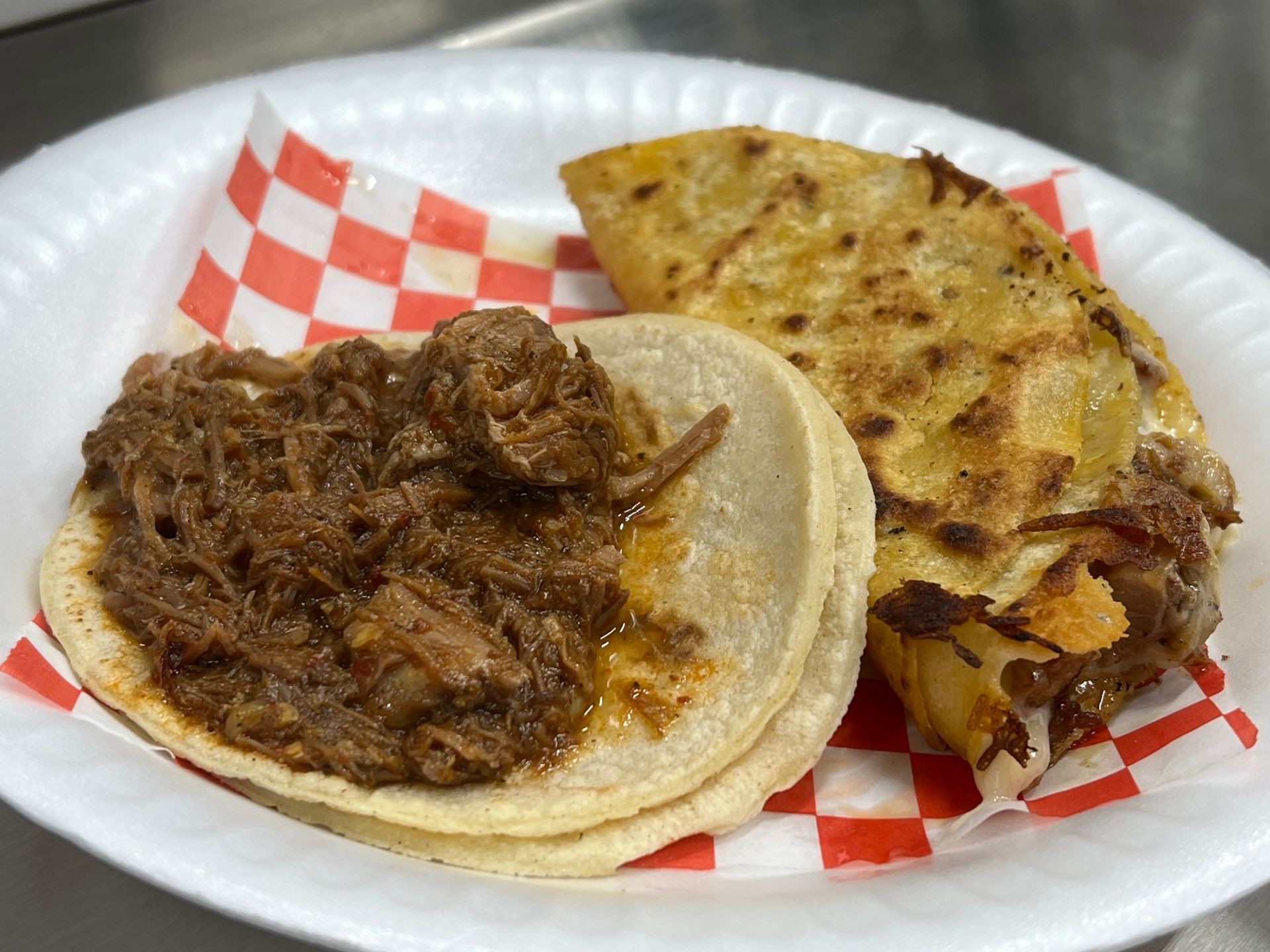 Plate with a birria taco and quesabirria, on a red checkered paper.