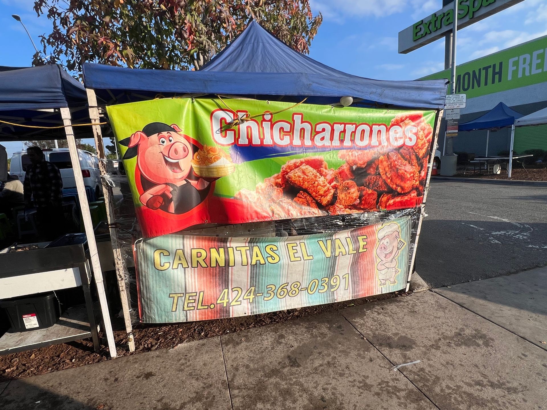 Street food stand with chicharrones banner and contact number, Carnitas El Vale.